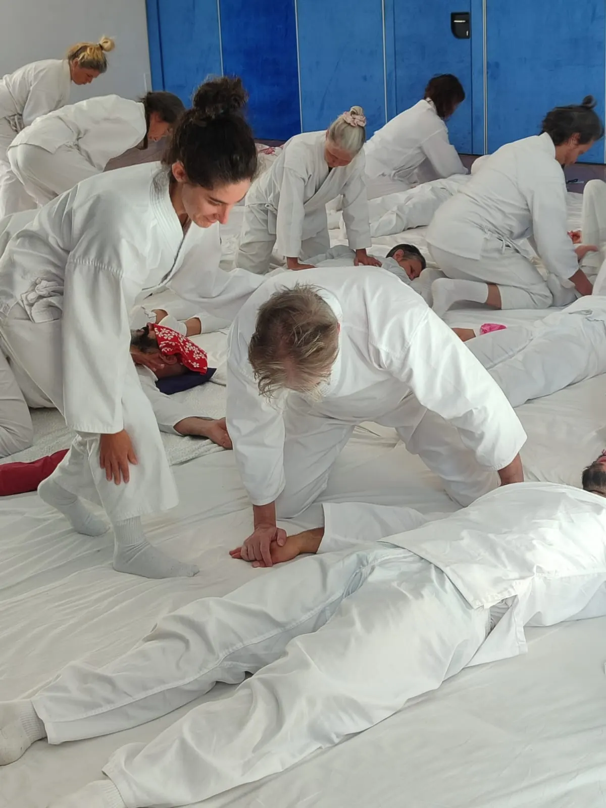 Gruppo in formazione: più coppie praticano Ohashiatsu® su futon in una sala.