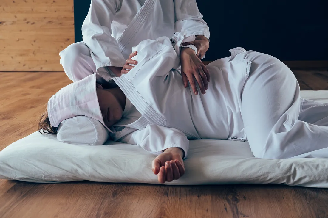Persona distesa su un fianco sul futon; le mani di Cecilia appoggiate sulla spalla e sull'anca durante una sessione di Ohashiatsu®.